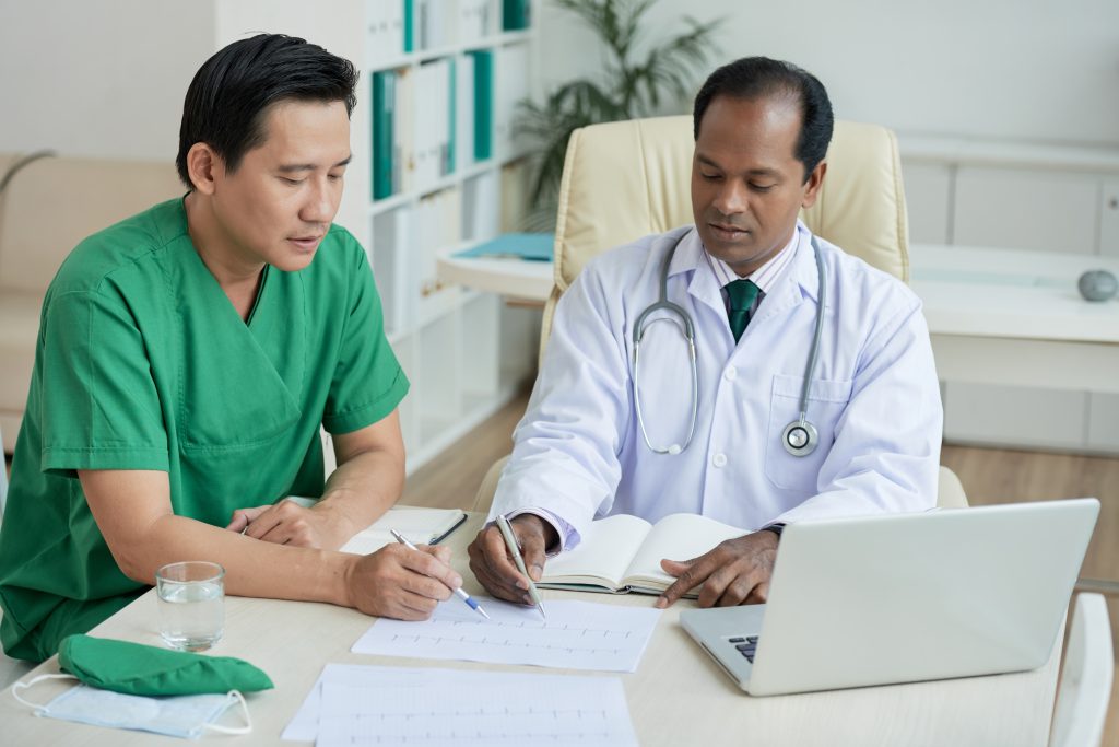Two doctors taking notes and discussing clinical billing and coding.